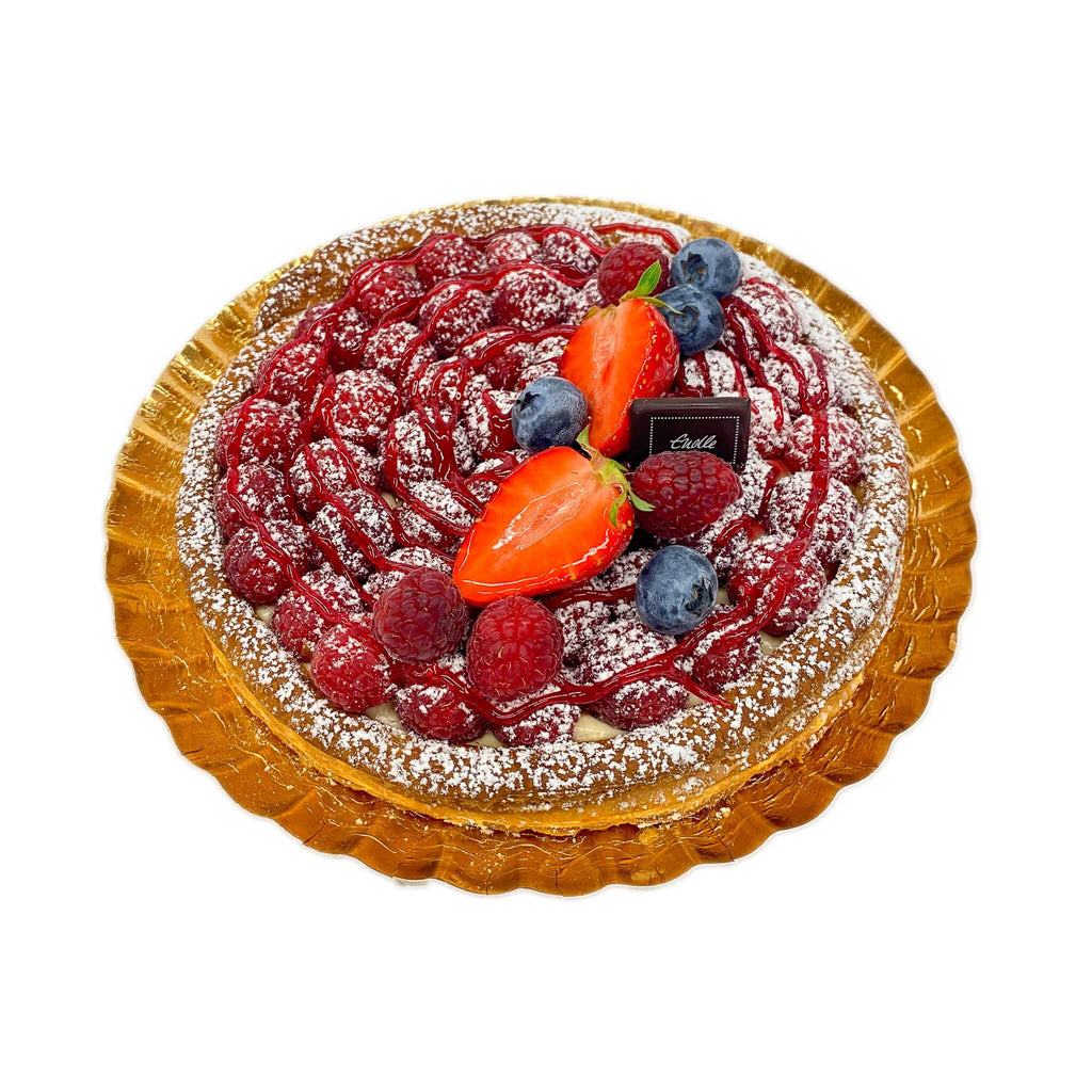 Tarte aus Butterblätterteig, gefüllt mit Vanillecreme, belegt mit Himbeeren und dekoriert mit Erdbeeren und Heidelbeeren auf Goldteller